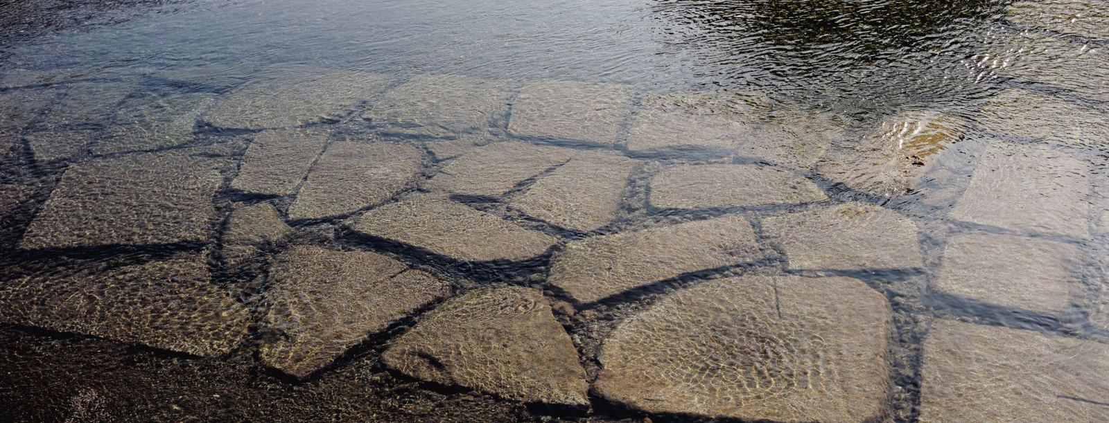 Flat stones under clear, rippling water